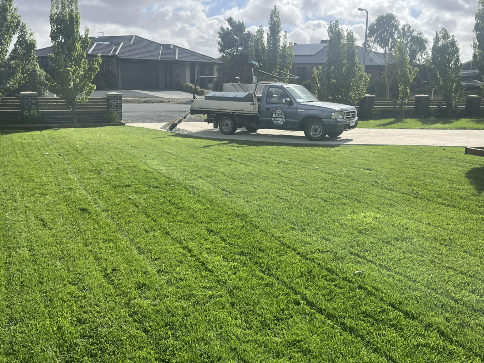 Freshly mowed striped lawn with the Jealous Neighbour Lawn Care ute